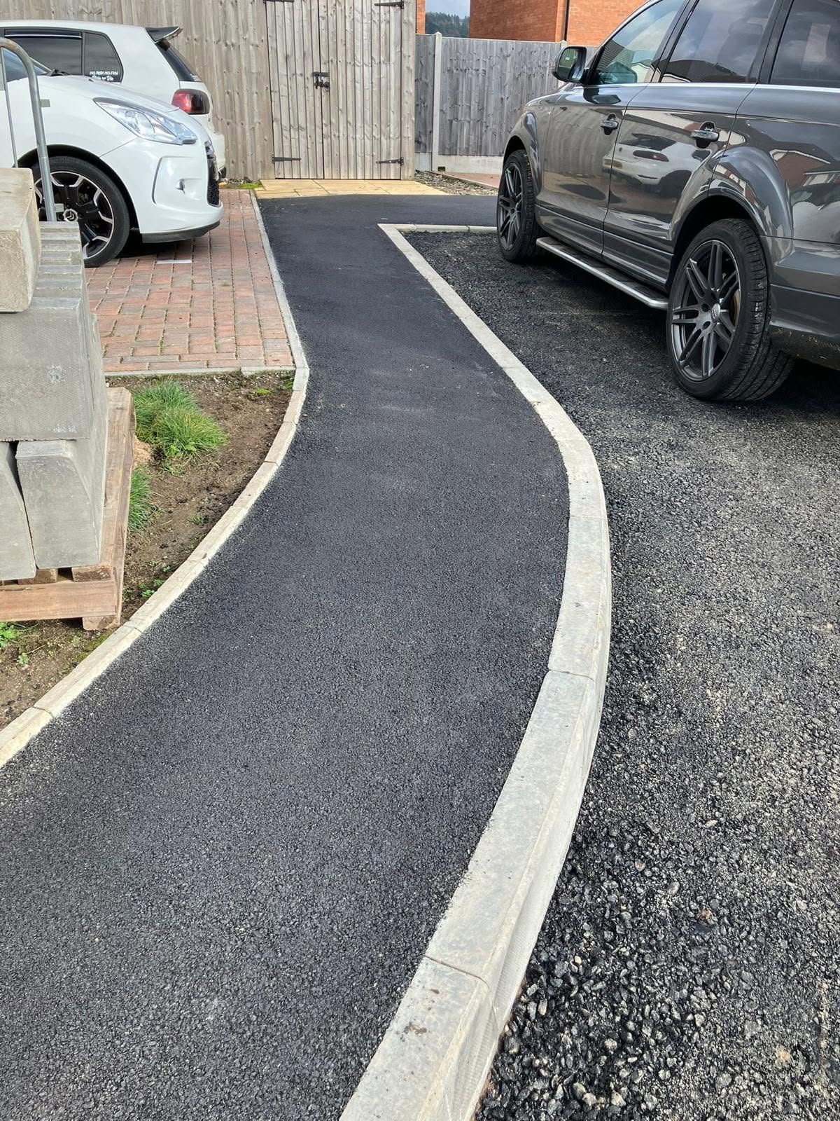 A parked car in a driveway adjacent to a curb