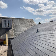 Rooftop with freshly installed slate tiles beside an older tiled roof.