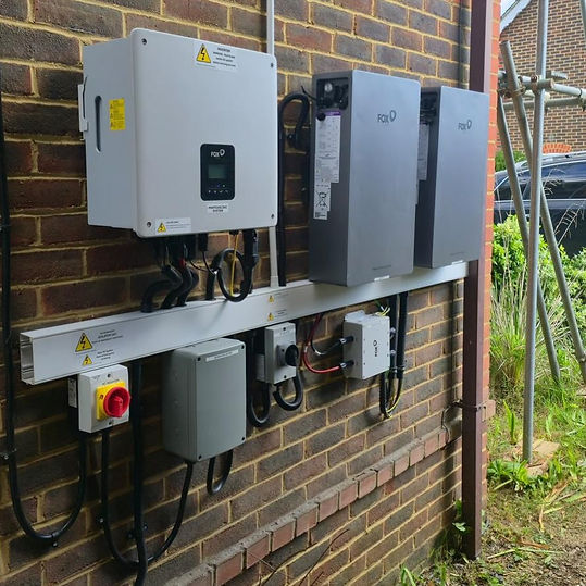 Solar power inverters and grey battery storage units mounted on an external brick wall
