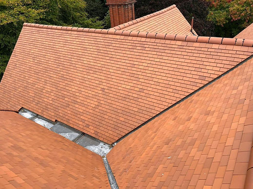 Aerial view of complex terracotta plain-tiled pitched roof featuring valleys, lead guttering, and a brick chimney stack