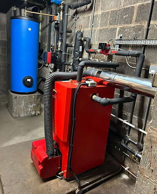 A boiler room with a blue water tank and red heating unit