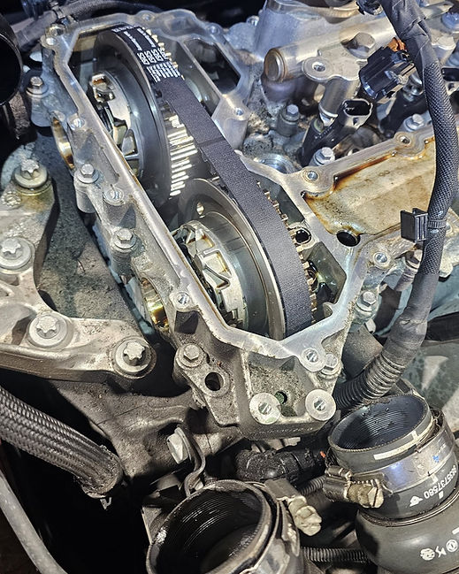 Close up of an open car engine showing two camshaft gears fitted with a black wet belt