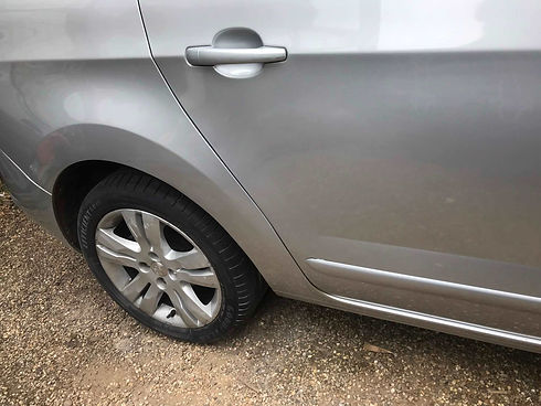 Side view of a silver car rear wheel arch and door showcasing professional mobile paint repair in Coventry