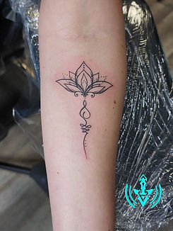 Delicate lotus flower tattoo on a forearm, intricate fine line details.