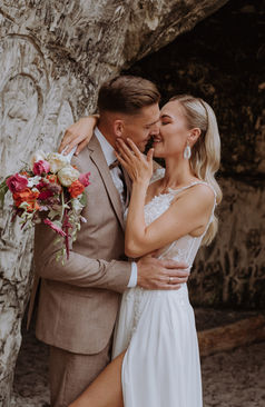 Zärtlicher Moment zwischen Braut und Bräutigam an rustikaler Steinwand - natürliches Paarfoto bei Hochzeit