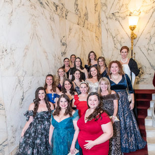 Large group of women in formal gowns, standing on a staircase