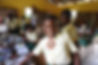 Smiling schoolgirl in yellow shirt smiles in classroom with other students.