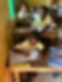 Children in classroom wearing yellow shirts, writing, focused on studies Projects Abroad Foun