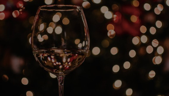 A wine glass at christmas with lights in the background.