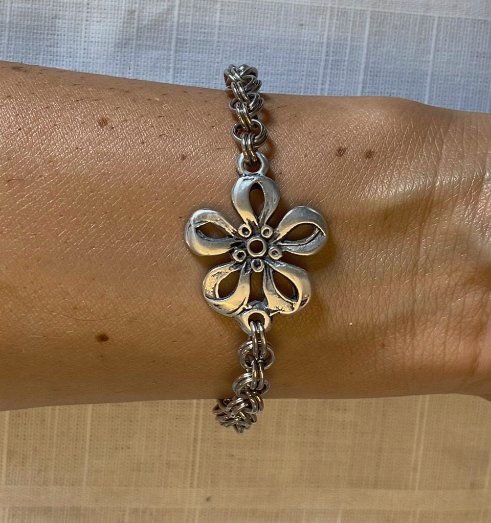 Woman wearing our Geranium Charm bracelet, featuring a silver geranium charm on silver chain from WildGeraniumJewelry.com