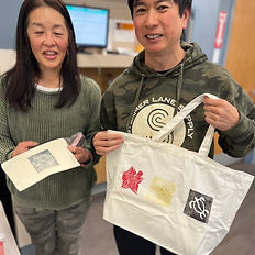 2 guests holding up their designs, on paper and a toge