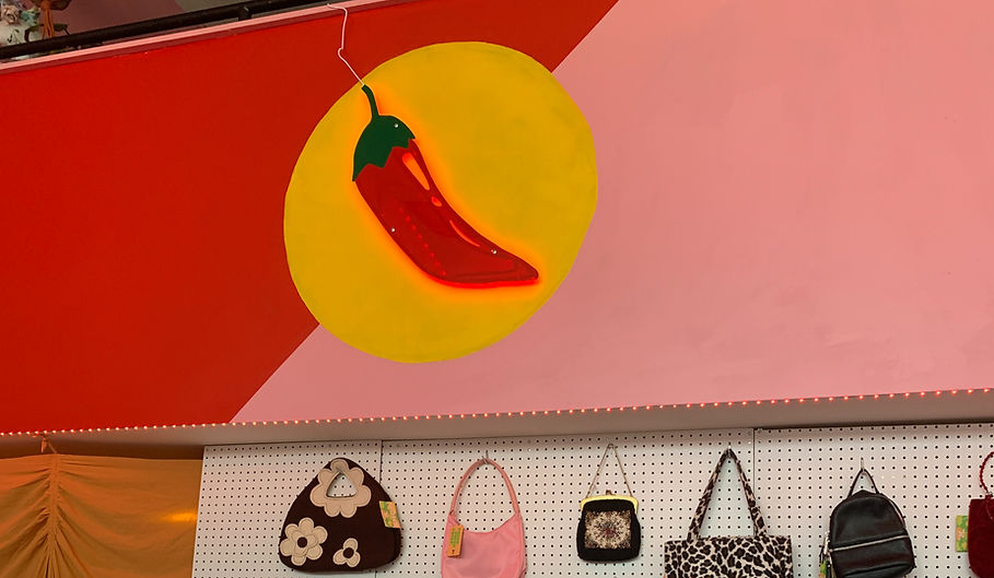 An image of a chilli pepper sign on a yellow, red, and pink background