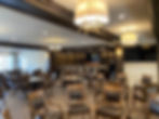 Elegant commercial dining area with wooden chairs and bar.