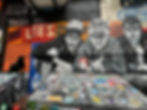 Black cat sitting on a dumpster in front of a Beastie Boys mural.
