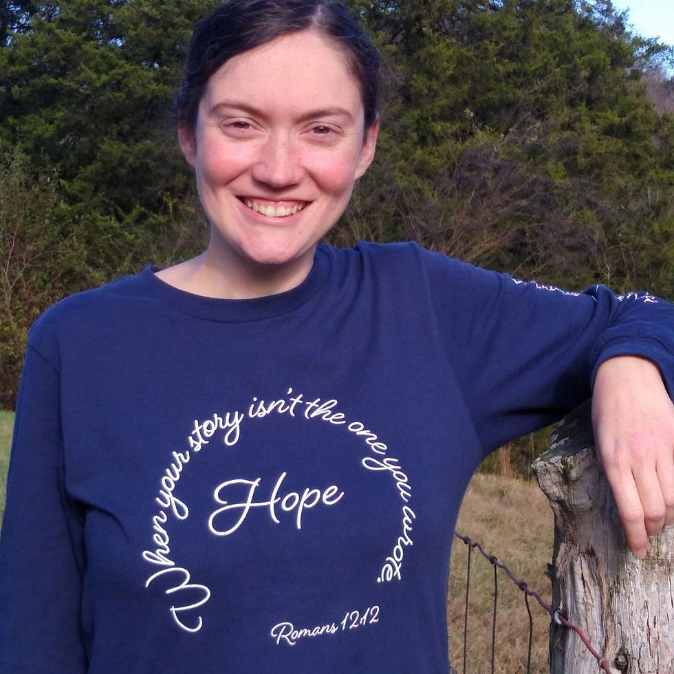 Smiling woman wearing a navy blue long-sleeve shirt with the words 'When your story isn't the only story' and 'Hope' embroidered on it.