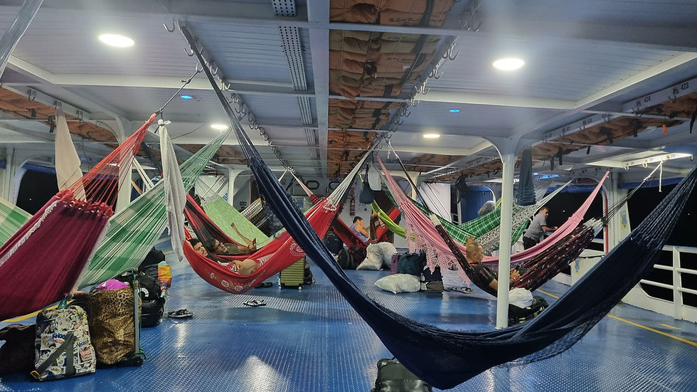 A dozen hammocks hang in an open air boat deck
