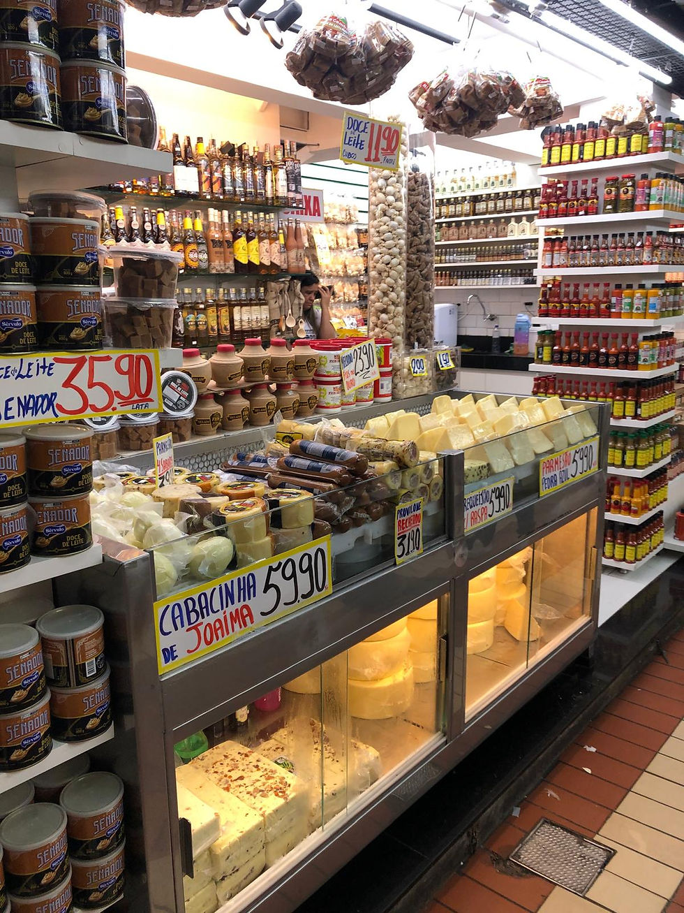 A store inside Mercado Municipal with shelves stacked with cheese, cachaca, hot sauces, and sweets