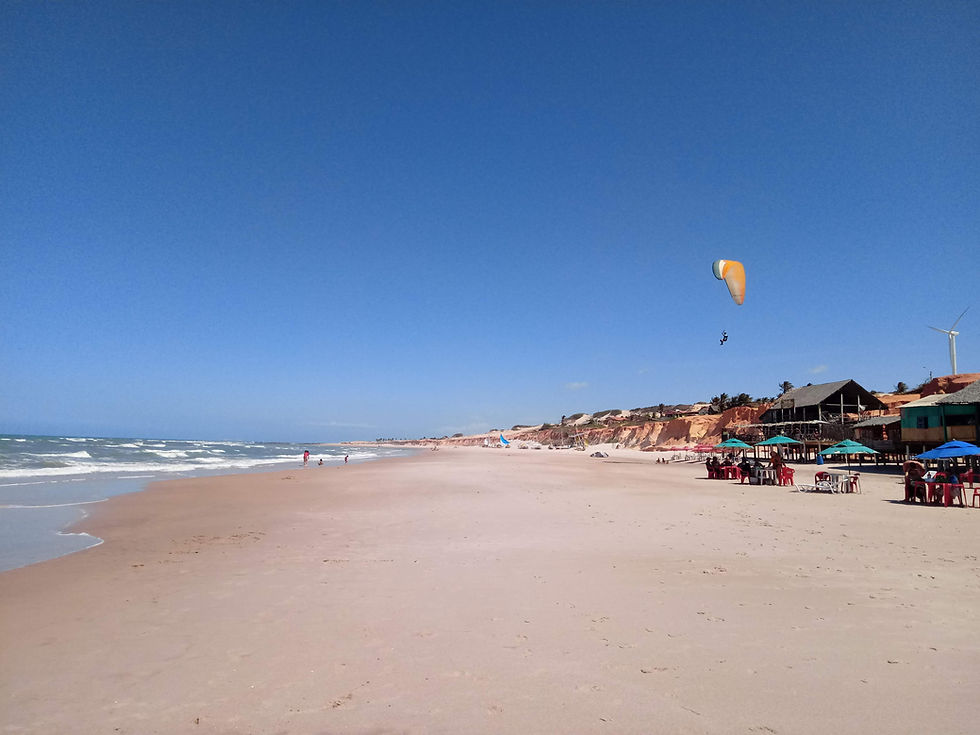 A yellow parachute in the sky hang-gliding over canoa quebrada beach