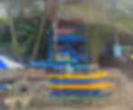A man sleeps in a hammock behind a stack of Surfboards, in front of a blue wooden shack, on Praia do Amor in Pipa