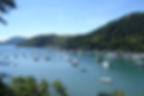 Dozens of boats on blue water surrounded by green mountains in Ubatuba