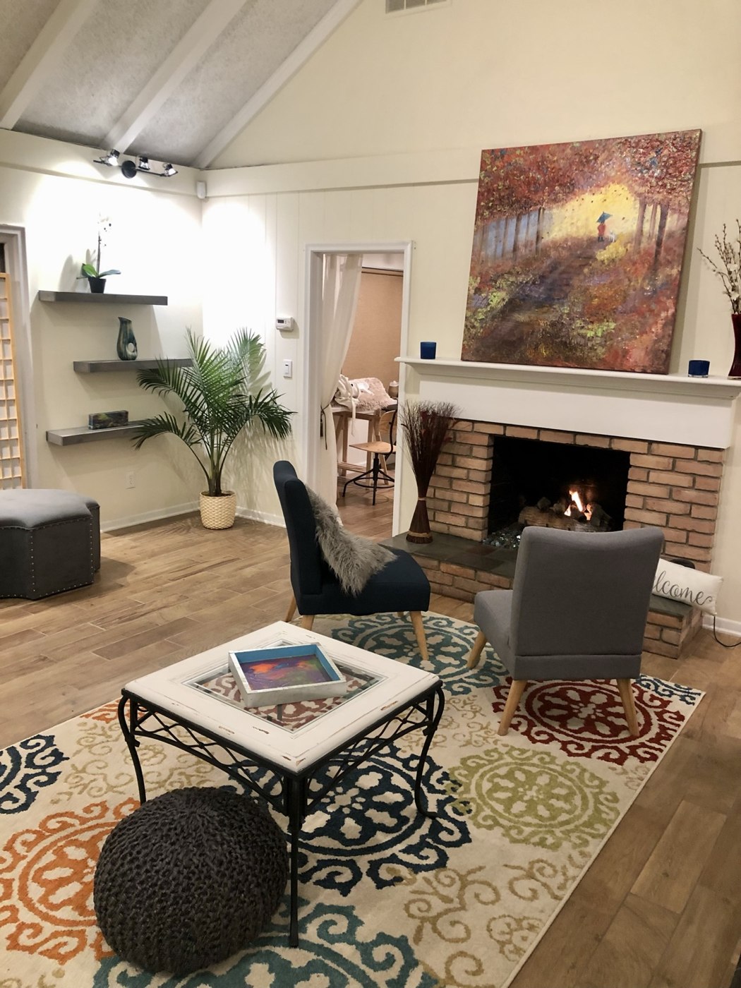 The Drake Center fireplace, comfortable chairs, colorful rug, and original artwork