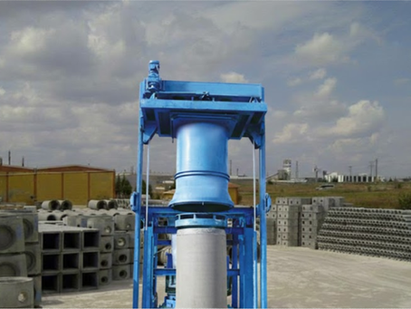 A blue concrete pipe machine is surrounded by finished concrete pipes, ready for delivery to the customer.