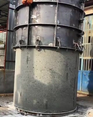 Steel mould being lifted off a large freshly cast precast concrete pipe section in an outdoor yard