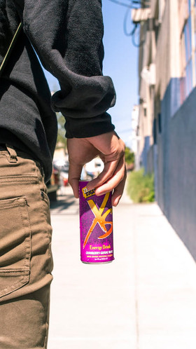 Man holding a can of XS walking in San Francisco