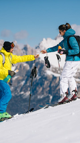 A couple on an adventure standing on a mountain slope exchanging XS products in the Dolomites