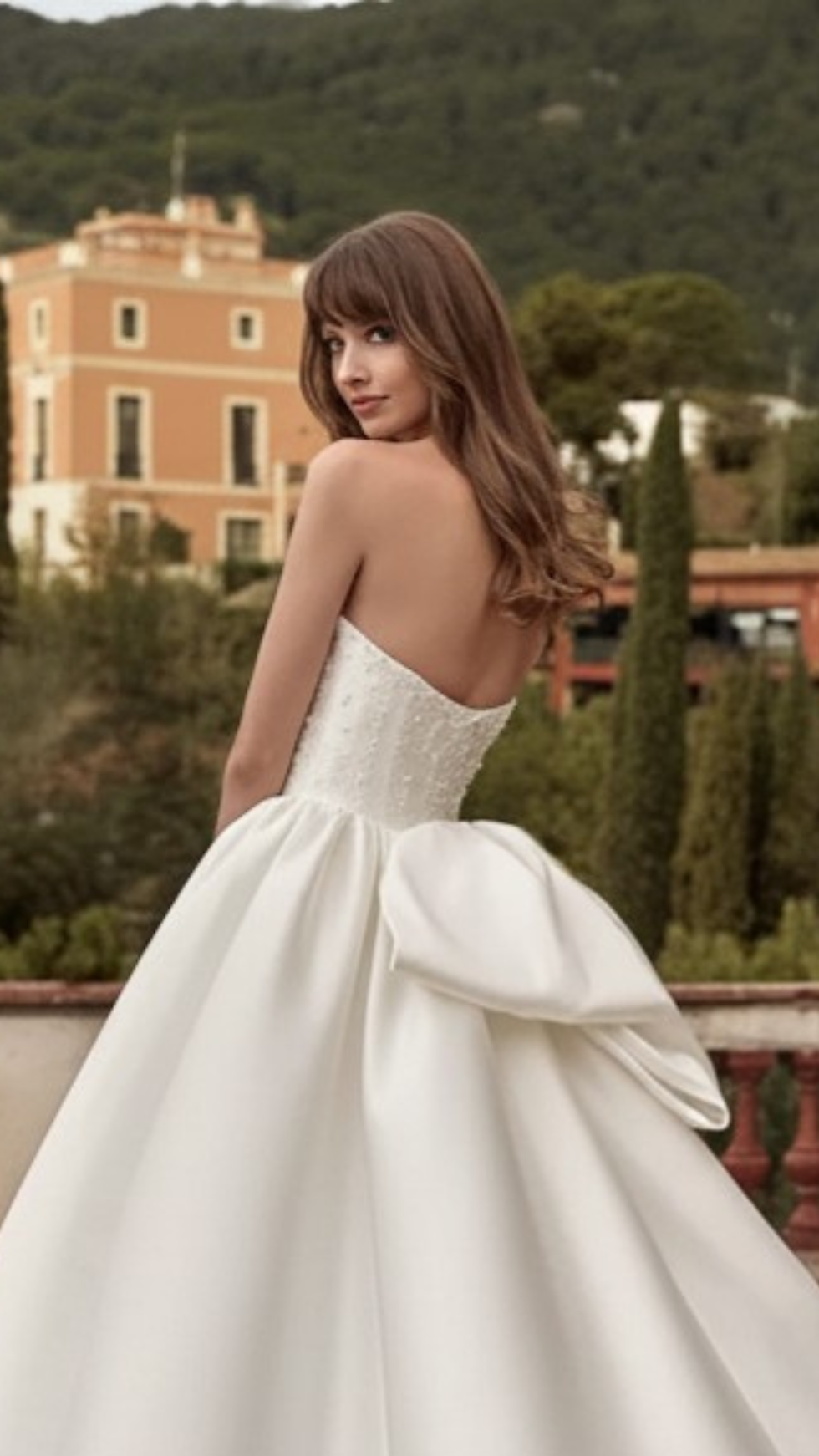 Vestido de noiva Nicole Milano disponível na Templo Fashion com costas abertas, corpete bordado em pedrarias e delicado laço na cintura, valorizando uma silhueta feminina e refinada.