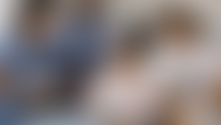 A woman sat in a hospital bed, surrounded by healthcare workers. All the workers are leaning in to listen.