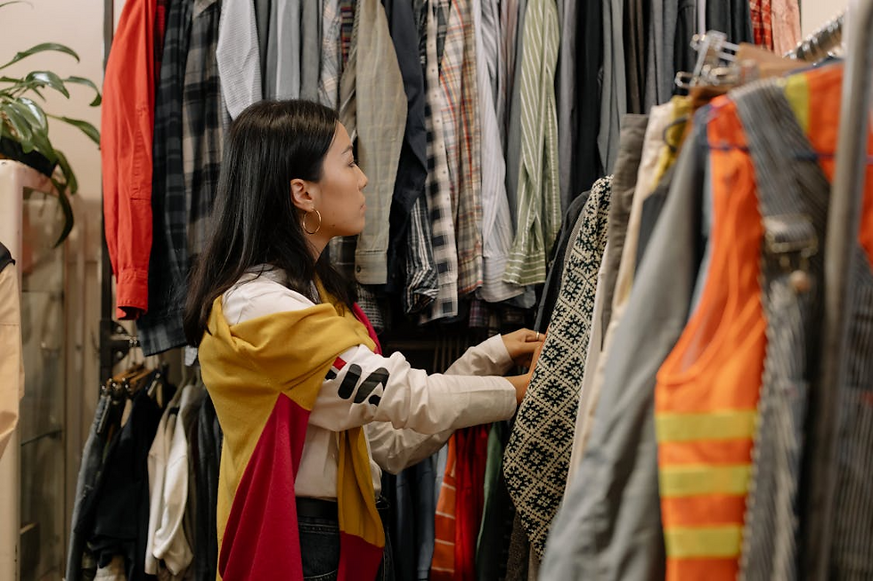Woman looking through railings packed with clothing.
