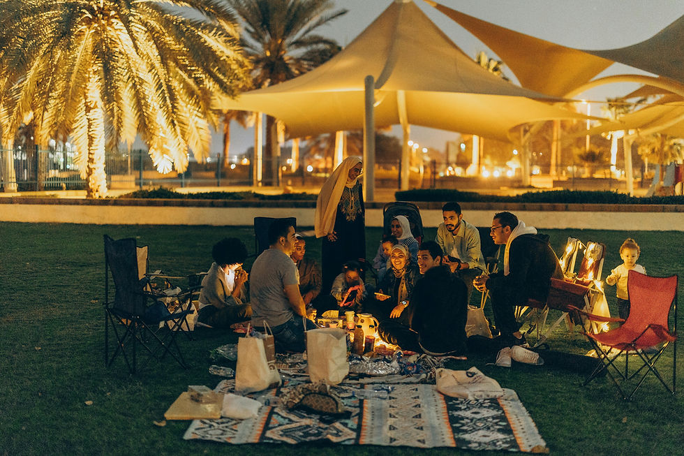 A large number of people are gathered together at a picnic and are sitting on the floor.
