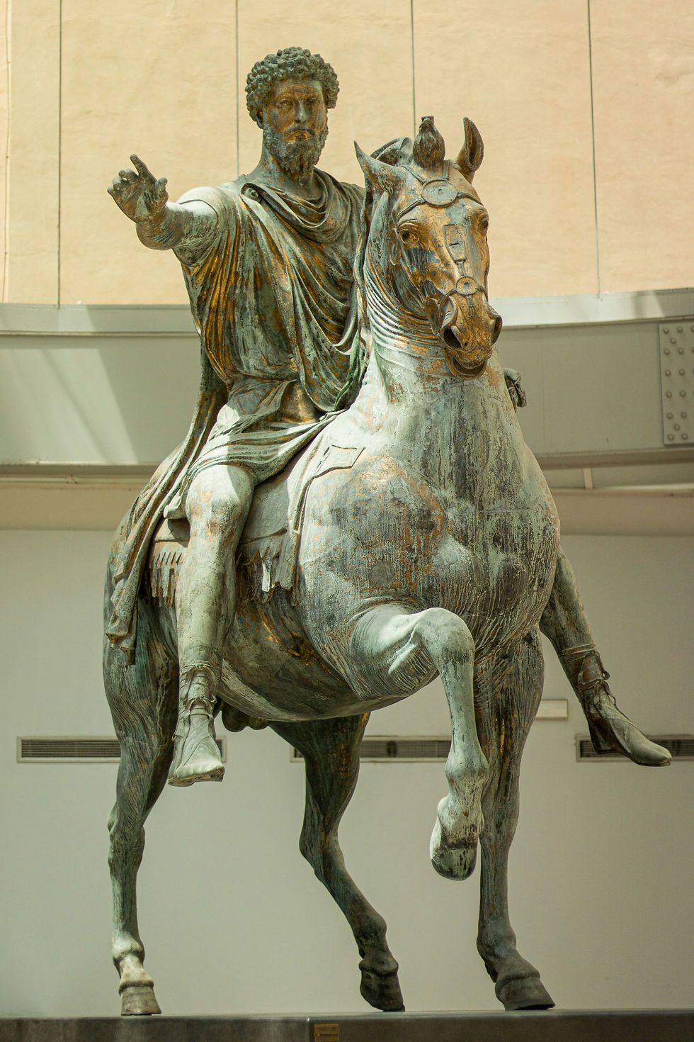 Bronze statue of a bearded man on a horse, arm raised in a commanding gesture, displayed indoors against a pale museum wall.