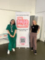 Image of Ellen (Author) and Kim standing beside a banner saying "The PMDD Project"