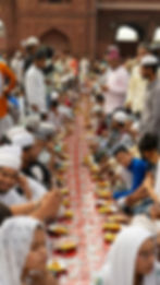 Large community gathering at a long table for Iftar celebrations.