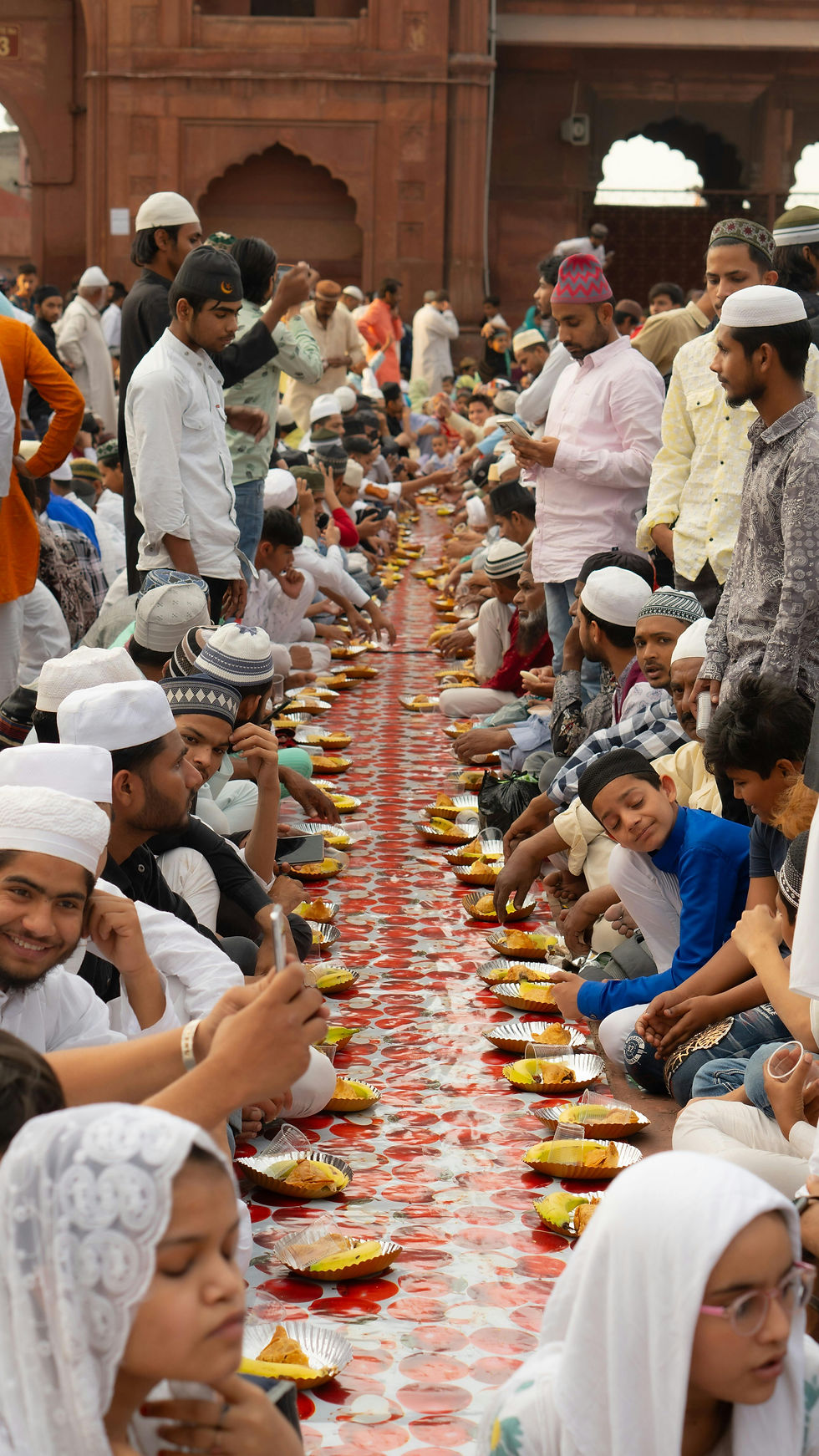 Large community gathering at a long table for Iftar celebrations.