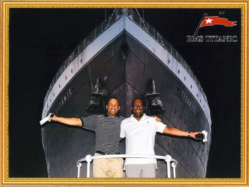 Image of author as an adult standing next to a friend holding each other's shoulders, posing in front of the RMS Titanic.