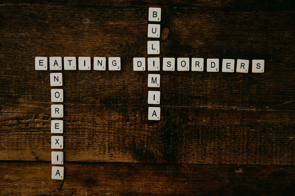 On a wooden table, Scrabble tiles are spelling out Eating Disorders, Bulimia, and Anorexia.