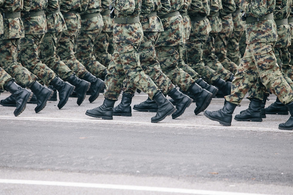 Men in brown and green camouflage uniforms are walking side by side in a parade. The image