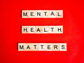 Scrabble tiles spelling Mental Health Matters on a bright red background.