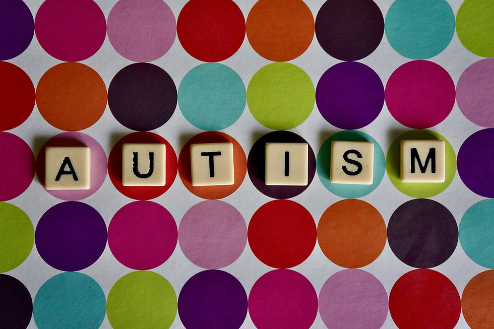 Letter tiles spell AUTISM on a colorful polka-dot background.