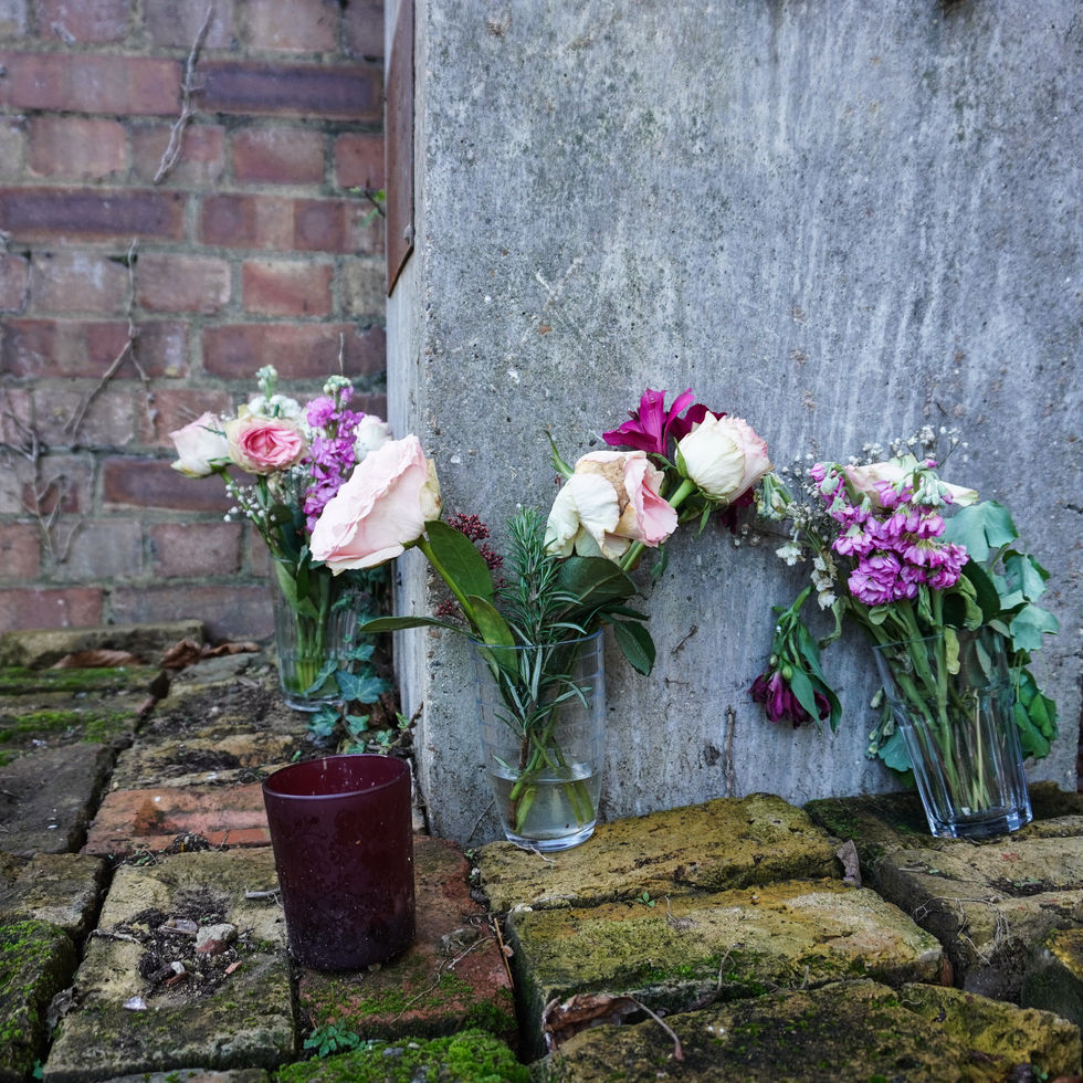 Three floral arrangements against a brick and concrete wall.