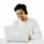 man smiling while wearing headset infront of his laptop