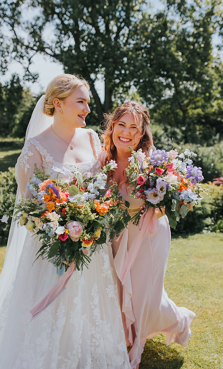 A bride and bridesmaid holding wedding flowers