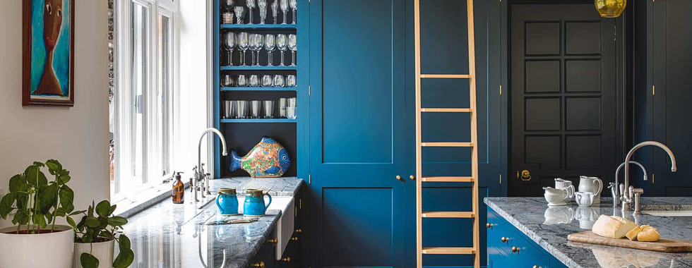 blue floor to ceiling kitchen cabinets in a traditional shaker style and large blue kitchen island with marble top and chrome taps