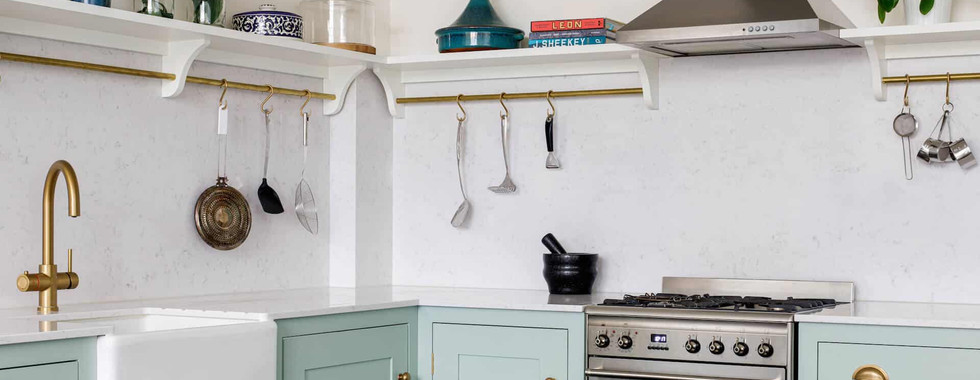 butler sink in a kitchen with gold tap and eau de nil colour cabinets