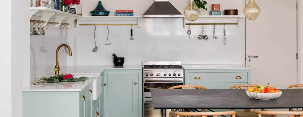 butler sink in a kitchen with gold tap and eau de nil colour cabinets