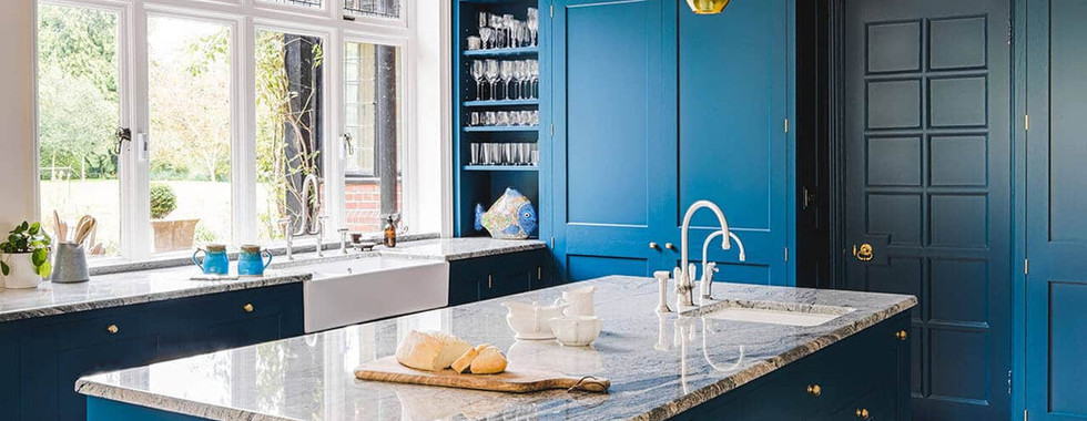 blue floor to ceiling kitchen cabinets in a traditional shaker style and large blue kitchen island with marble top and chrome taps