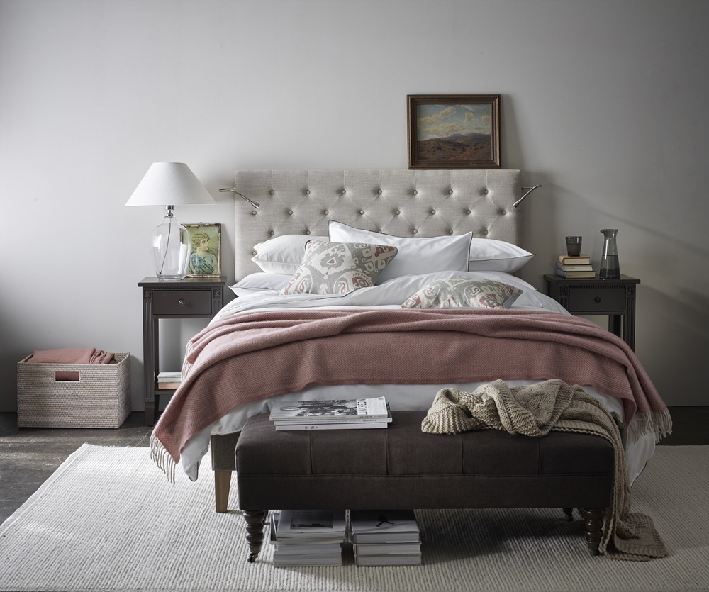 Shaftesbury Glass Lampstand by Neptune on a small bedside table and next to a linen headboard bed with pink throw and a muted colour palette